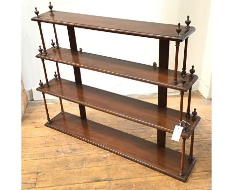 An Edwardian mahogany four tier graduated wall shelf, each shelf raised on turned tapered columns with urn style finials (78c