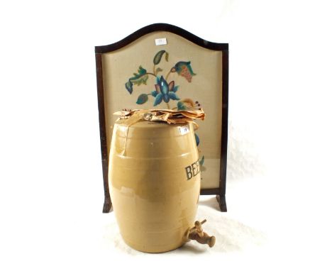 A stoneware beer barrel and a woolwork firescreen