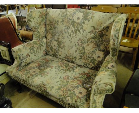 An Edwardian upholstered wing 2-seater sofa on cabriole legs.