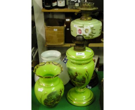 A green glass oil lamp with decorative panels and a brass oil lamp with glass font and shade.