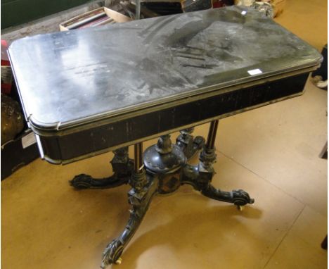 A Victorian ebonised rectangular foldover card table, raised on a quadruple carved and fluted base on sabre legs.