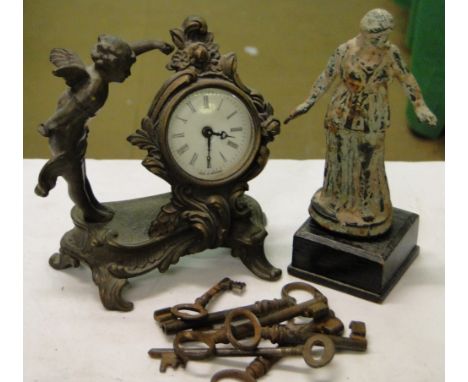 A small brass cased clock with cherub figure, another figure, and various keys.