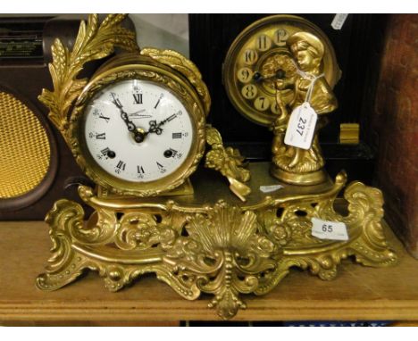 A cast brass clock on ornate plinth surmounted by a figure.