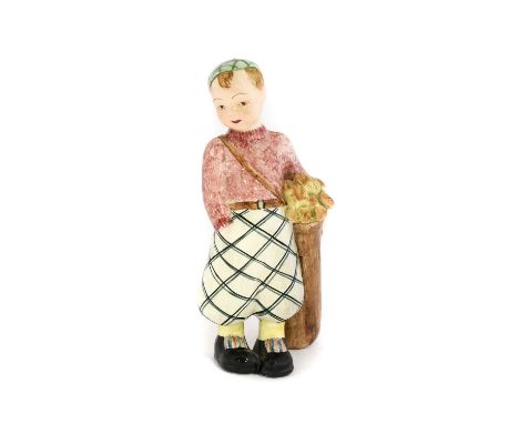 A Staffordshire Goldscheider Figure of a Boy Golf Caddy, circa 1940s, wearing check trousers, pink sweater and yellow socks, 