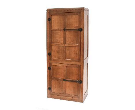 Robert Mouseman Thompson (1876-1955): An English Oak Panelled Cupboard, penny moulded top, with two sections, the top cupboar