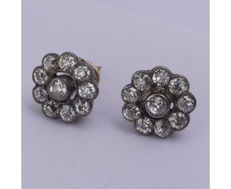 A pair of diamond flowerhead cluster Earrings, the old cut stones millegrain set in white metal and with 14ct gold screw fitt