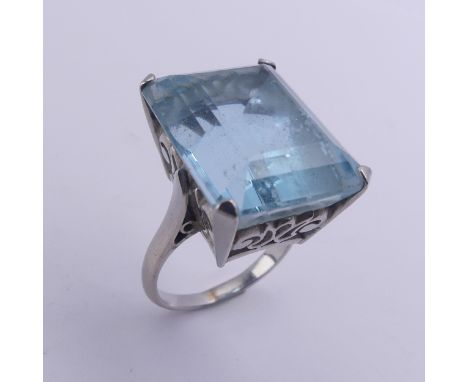 A large aquamarine Dress Ring, the stone approx. 20ct (18mm x 14.4mm x 11.3mm) mounted in unmarked white metal, tested as pla