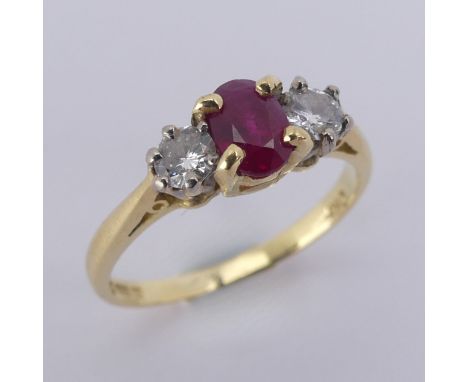 A three stone ruby and diamond Ring, the central oval facetted ruby 5.9mm with a small circular diamond on either side, all m