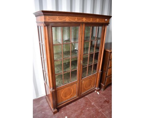 A late 19th or early 20th Century mahogany display cabinet having inlaid freeze and column supports, with double door , glaze