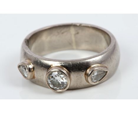 Diamond three stone ring with an old cut diamond flanked by two pear cut diamonds in raised collet setting on wide band.  Rin