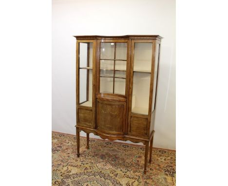 Edwardian inlaid mahogany display cabinet with shelved interior enclosed by central concave glazed door flanked by glazed pan