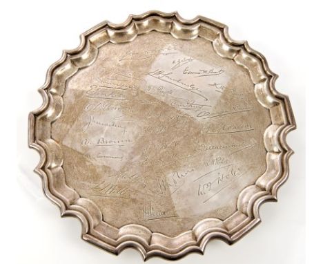 George V silver salver of circular form, with piecrust border and scroll rim with engraved facsimile signatures, on three ree