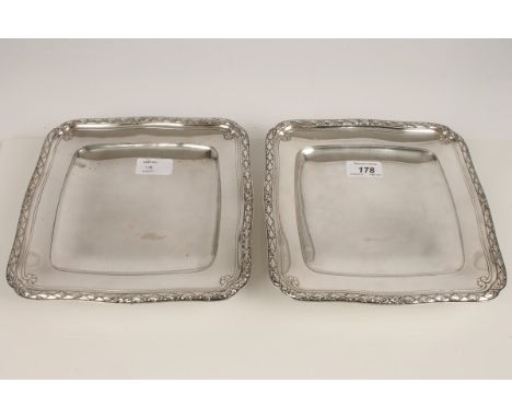 Pair French silver plated dishes of square form, with raised scroll and foliate borders and dished centres, on circular stepp