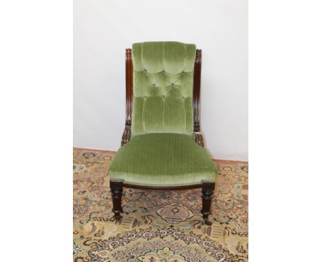 Victorian mahogany framed easy chair with green buttoned upholstery, on turned front legs and ceramic castors