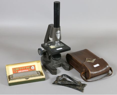 A students microscope and a boxed harmonica along with a cased camera and a door knocker.