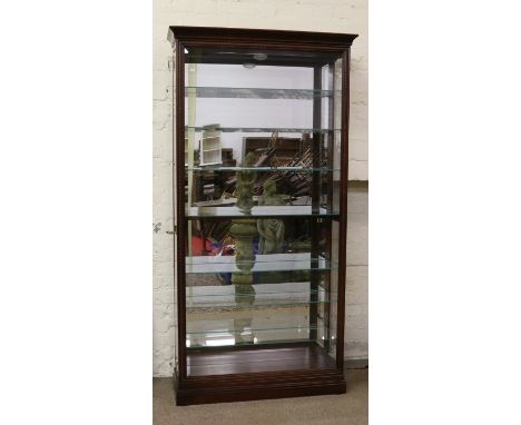 A Howard Miller carved mahogany tall standing display cabinet with mirrored interior and light bevel edge glazing having two 