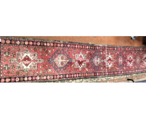 CAUCASIAN CARPET RUNNER WITH NINE MEDALLION CENTRAL RESERVED ON A RED GROUND 53CM X 315CM APPROX (SIGNS OF WEAR)