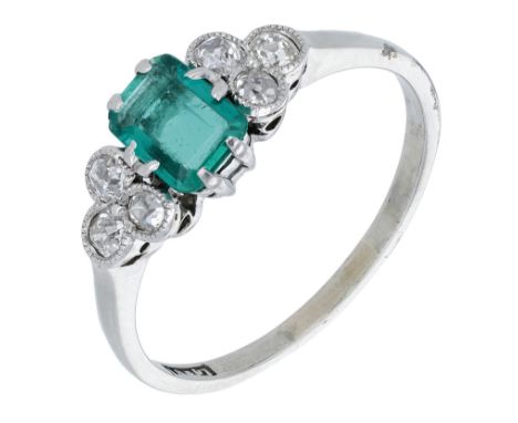 An emerald and diamond ring, the cut-cornered step-cut emerald between trios of brilliant-cut diamonds, stamped ‘18&PT’, ring