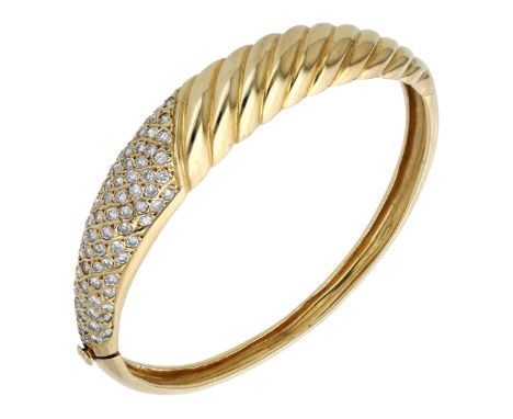 A diamond bangle, the tapered bombé style bangle set to the front with a of panel brilliant-cut diamonds and with diagonally 