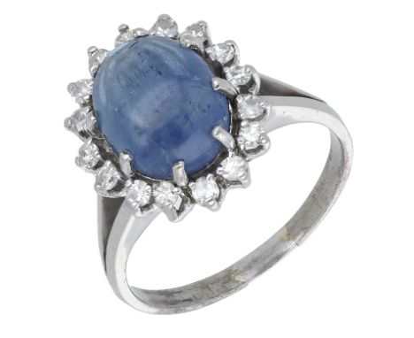 A sapphire and diamond cluster ring, the oval sapphire cabochon claw set within a surround of single-cut diamonds, total diam