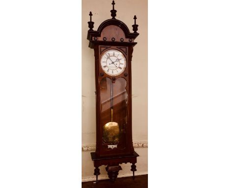 A 20th century mahogany frame Vienna wall clock, arch moulded cornice mounted with turned finials, above a circular over an a