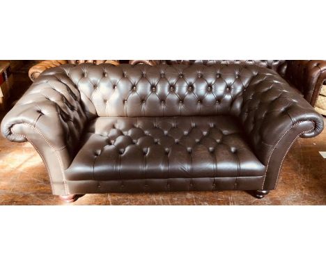 A 20th Century Chesterfield faux leather sofa, scrolling button back, arms and seat, raised on turned feet. 75cm H x 191cm W 