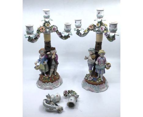 A pair of late 19th Century Continental ceramic candlesticks, with two figures and floral decoration, marks to the base, each