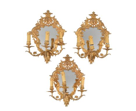 
	
		A set of three gilt metal three light girandoles in Regence style, late 19th/early 20th century, of cartouche form, the 
