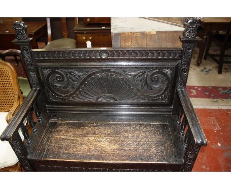 A late 19th century oak monk's bench with carved panelled back and hinged seat. 112cm wide x 114cm high.