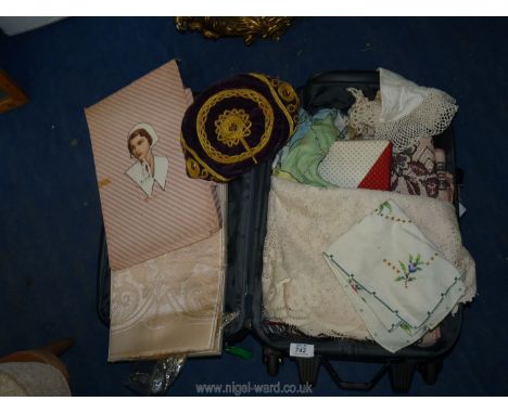 A small suitcase of linen, crochet work and boxed vintage tablecloths. 