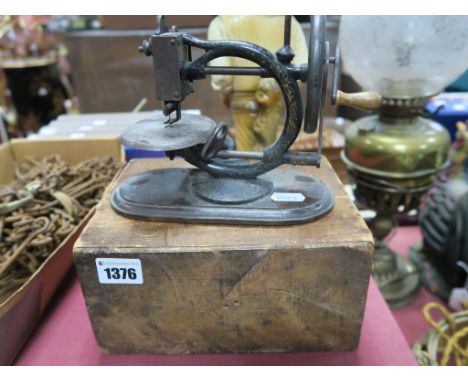 A Circa 1900 Sewing Machine, of small proportions, 'C' scroll frame with rubbed gilt decoration, height 15cm, mounted on an o