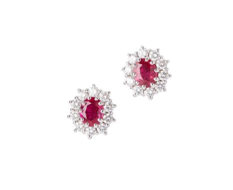 A pair of ruby and diamond set cluster earrings each claw set with an oval-cut ruby, in a single border of small round brilli