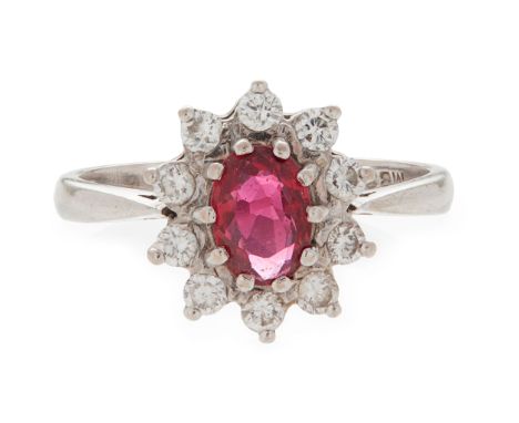 A ruby and diamond set cluster ring claw set with an oval-cut ruby, in a border of ten small round brilliant-cut diamonds, to