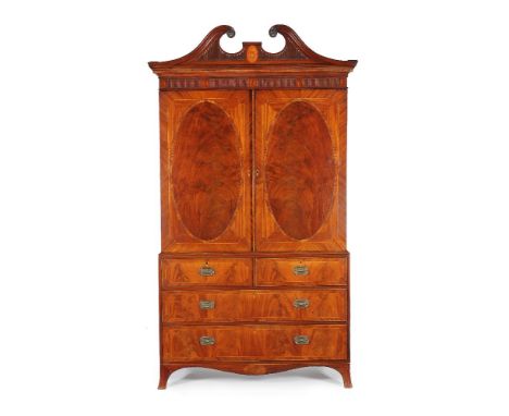 ϒA George III mahogany and tulipwood banded linen press, circa 1790, the fluted 'swan neck' pediment incorporating carved pat