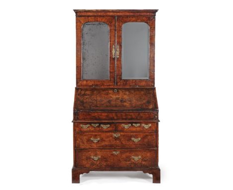 A George I walnut and featherbanded bureau bookcase, circa 1720, the moulded cornice above a pair of mirror panelled doors, o