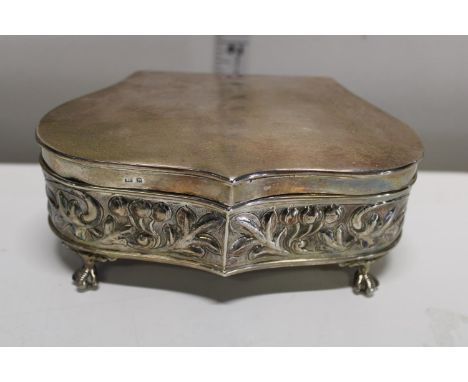 An Edwardian silver repousse heart shaped jewellery casket with hinged lid. Decorated with scrolling foliage, upon claw feet.