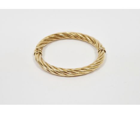 9k yellow gold hinged bangle of twisted design, stamped 375, approximately 6.5cm wide and 11.2 grams