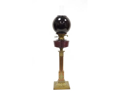 Victorian copper and brass Corinthian column oil lamp comprising a globular red glass shade, reeded red glass reservoir, clea