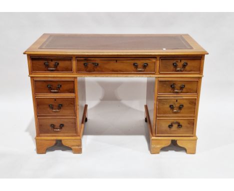 Yew wood twin-pedestal desk, the brown leather inset top with thumb moulded edge over an arrangement of seven drawers and rai