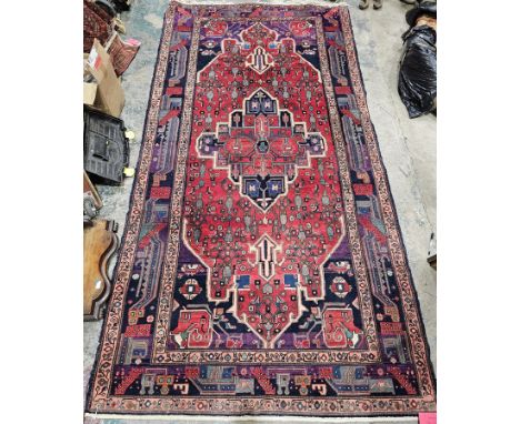 Iranian red ground carpet with large central geometric medallion on stylised geometric field, midnight blue spandrels, multip