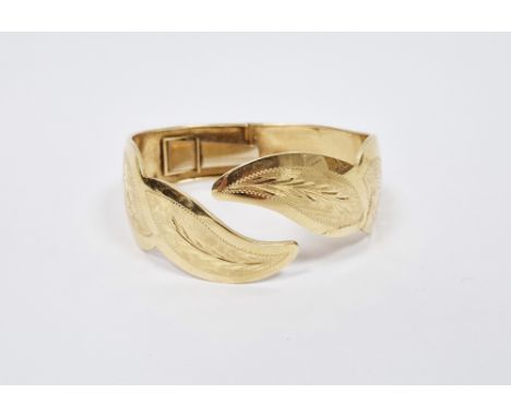 18k yellow gold hinged torque bangle, the front shaped in the form of leaves with brushed and foliate decoration, stamped 750
