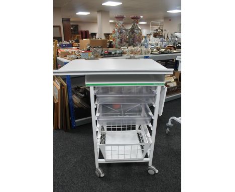 A metal medical trolley with two plastic trays and adjustable shelf and wire mesh basket