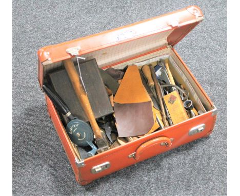 A vintage leather case containing upholstery hand tools and leather pieces 