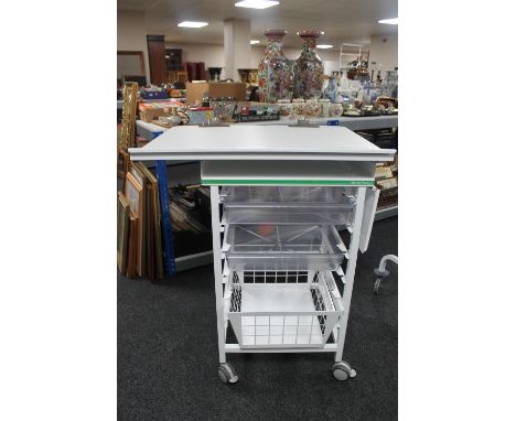 A metal medical trolley with two plastic trays and adjustable shelf and wire mesh basket