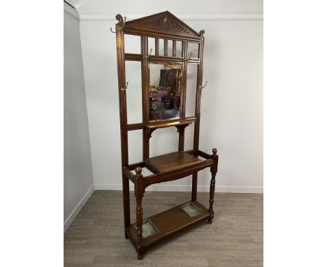 LATE VICTORIAN OAK HALL STAND, the carved arched pediment over hanging hooks, central bevelled mirror and shelf, above a furt