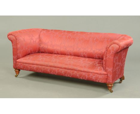 A Victorian Chesterfield settee, upholstered in red foliate patterned material with piping and raised on turned front legs wi