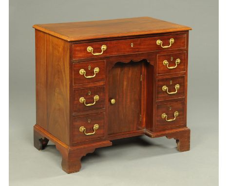 A George III mahogany kneehole desk, with moulded edge, frieze drawer, recessed cupboard and three further drawers to each pe