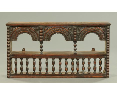 An antique oak spindled and arched wall shelf.  Width 92 cm. 