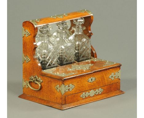 An Edwardian oak three decanter tantalus, with games drawer and silver plated mounts. 