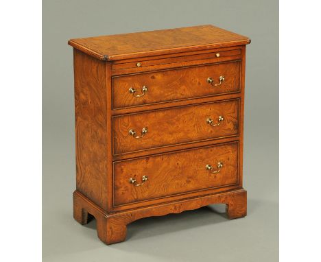 A Georgian style burr walnut chest of drawers, with slide and three drawers with brass drop handles and raised on bracket fee